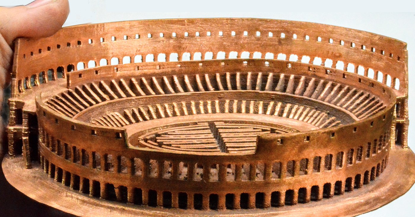 3D printed model of the Roman Coliseum in copper, showcasing intricate details and layered construction, highlighting advancements in FFF metal 3D printing technology.