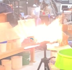 Flame shooting from a metal 3D printing setup in a workshop, illustrating the sintering process related to Filamet™ metal filament.