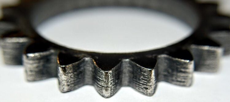 Close-up of a metal gear showcasing intricate details, relevant to affordable metal 3D printing technology and the capabilities of The Virtual Foundry's Filamet™.