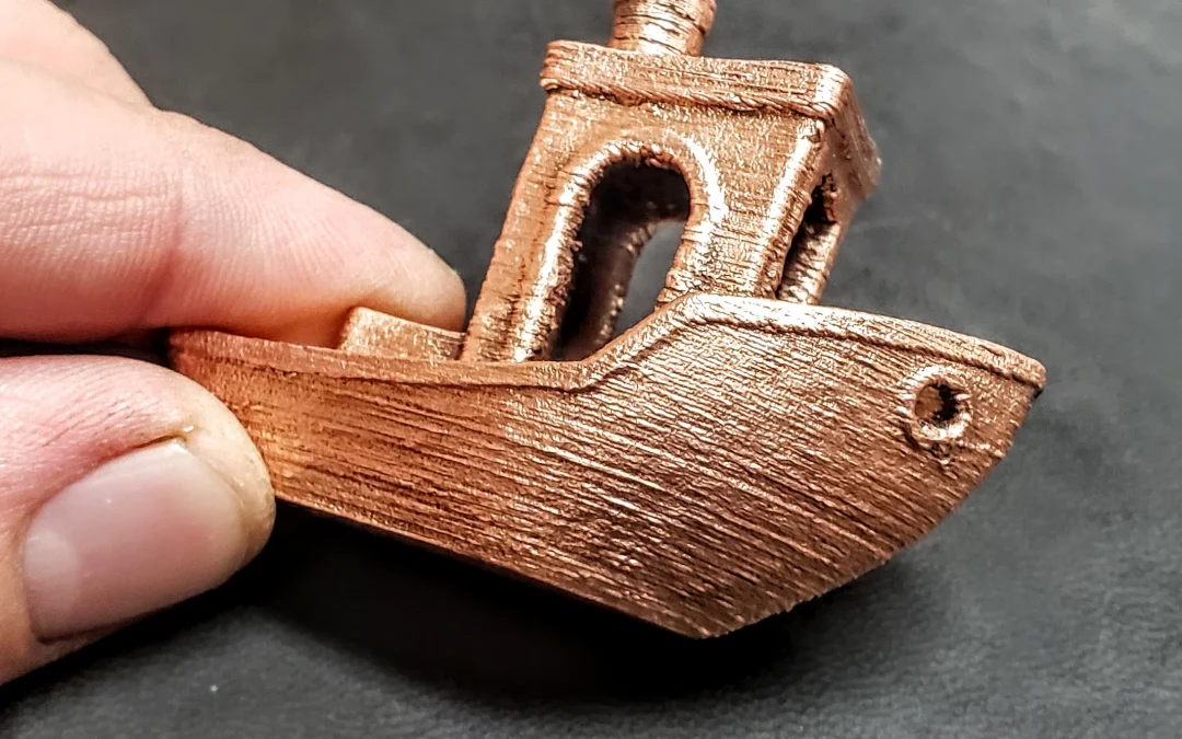 3D printed metal boat model made with Filamet™ metal filament, held by a hand, showcasing the texture and detail of metal 3D printing technology.