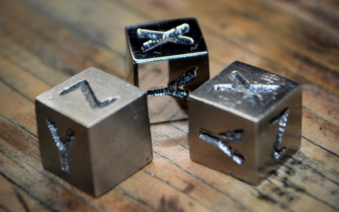 Metal letter stamps showcasing intricate designs, positioned on a wooden surface, representing tools for metal 3D printing and educational applications related to Filamet™ metal filaments.