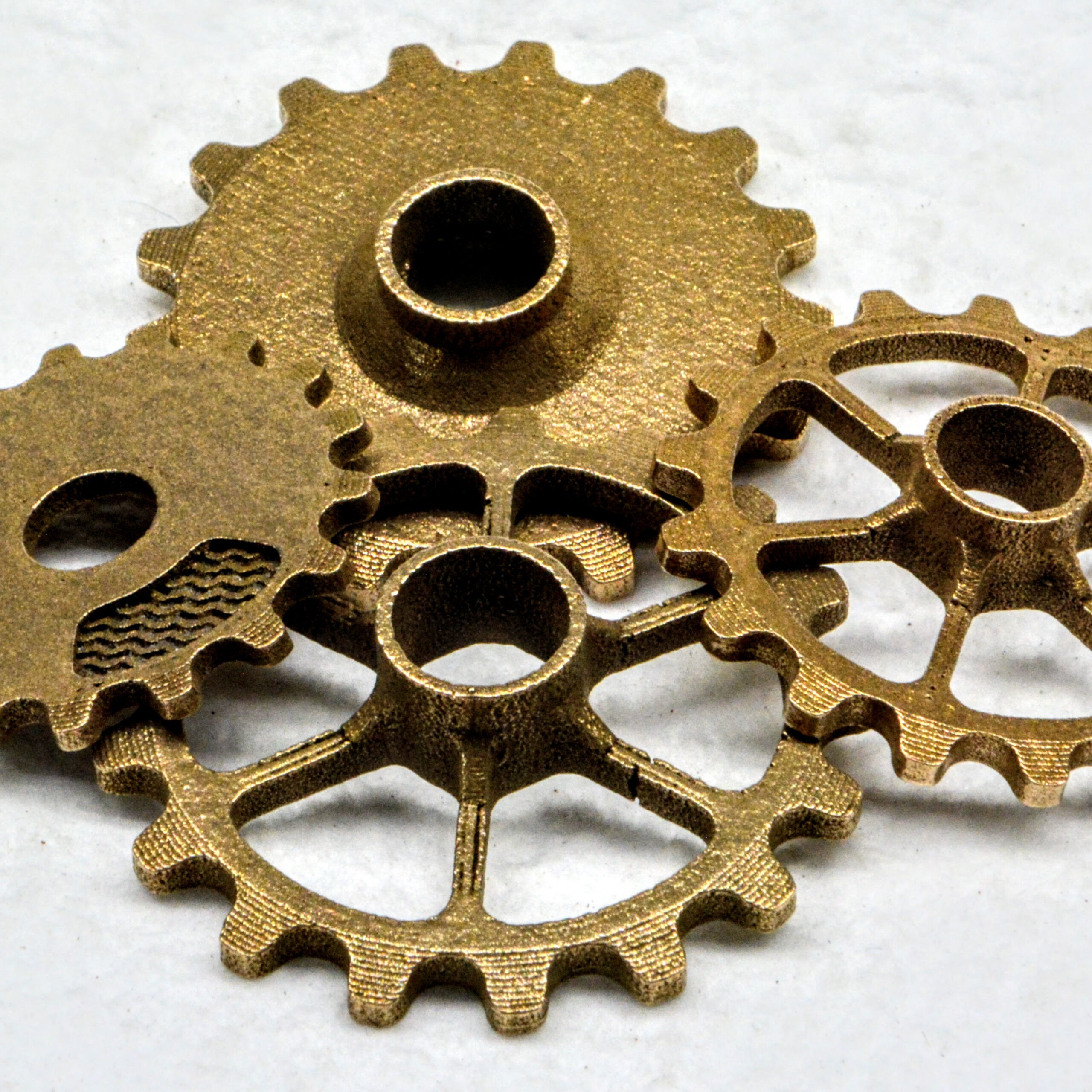 Bronze gears showcasing intricate designs and textures, emphasizing metal 3D printing applications with Filamet™ materials.